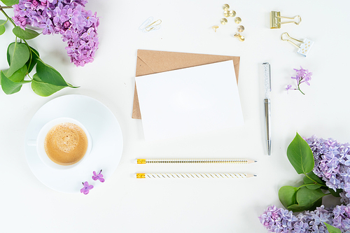 Flat lay top view home office workspace - blank card with lilac flowers on white background