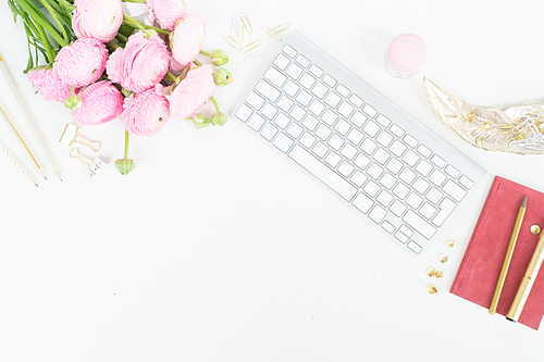 Flat lay home office workspace - modern keyboard with female accessories and ranunculus flowers, copy space on white background