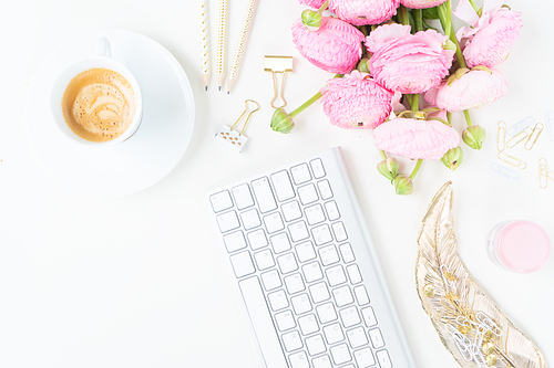 Flat lay home office workspace - modern keyboard with cup of coffee and pink ranunculus flowers