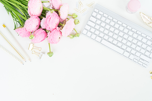 Flat lay home office workspace - modern white keyboard with female accessories and ranunculus flowers