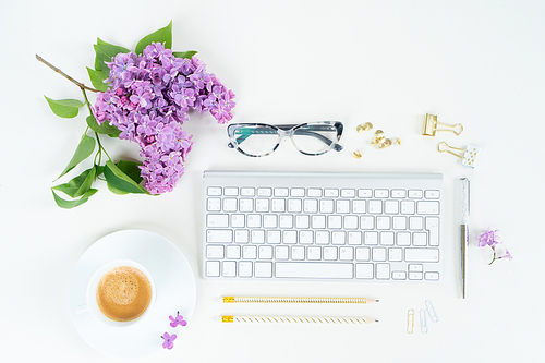 Flat lay top view home office workspace - modern keyboard with lilac flowers on white background