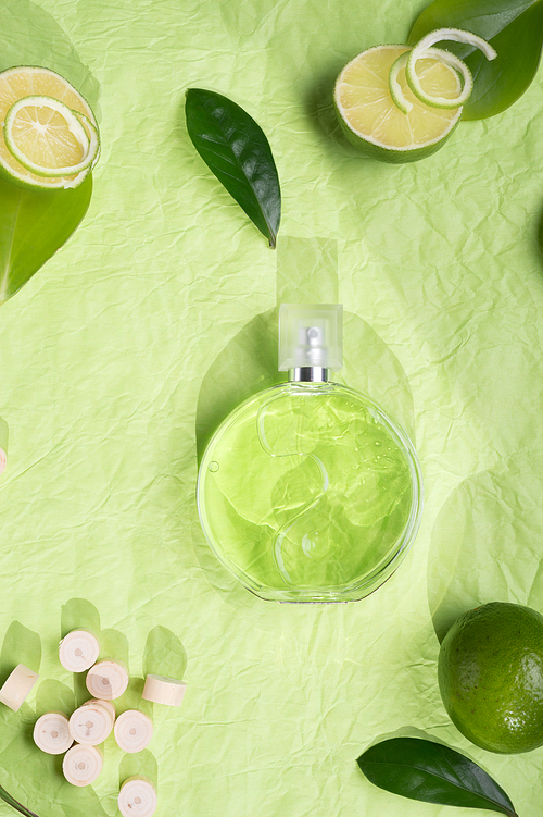 perfume bottle around ingredients  on green background. flat lay