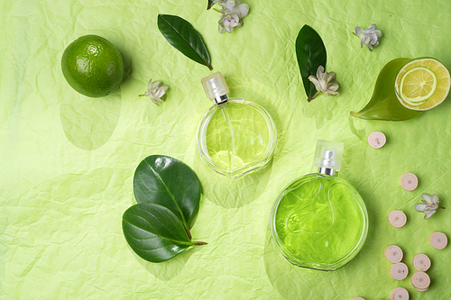 perfume bottles around ingredients  on green background. flat lay.copy space