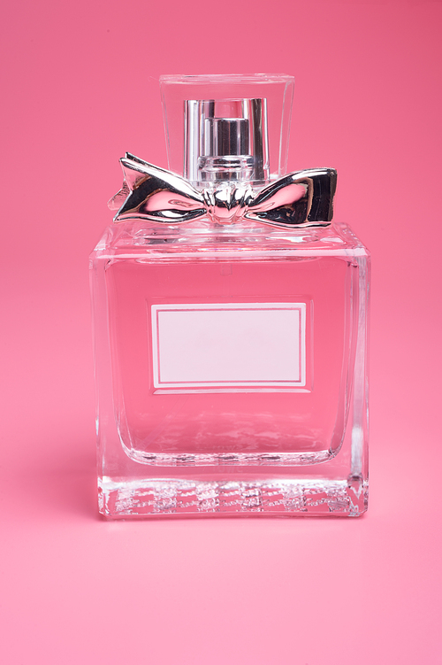 perfume bottle   around flowers on  pink   background. close up