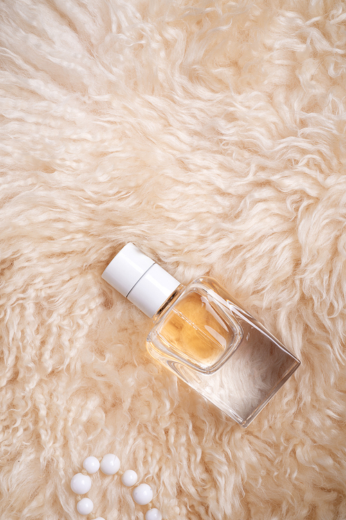 fragrance bottle at   sheepskin fur.  glamour concept. flat lay