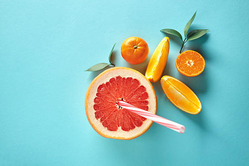 Composition of grapefruit, mandarin and pieces of orange with leaves on a blue paper background top view. The concept of a vitamin drink. Copy space