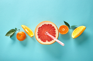 Ingredients for the preparation of freshly squeezed juices and smoothies from oranges, mandarin and grapefruit are lined in a row on a blue background, flat lay