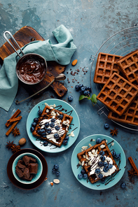 Chocolate belgian waffles with ice cream and fresh blueberry on blue background, top view