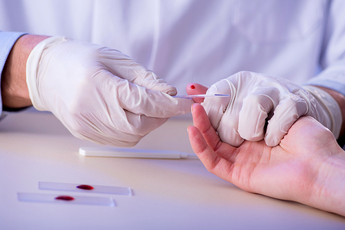Doctor taking blood samples from finger