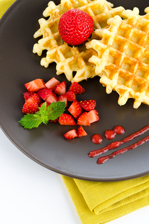 Belgium waffles with strawberries on plate.