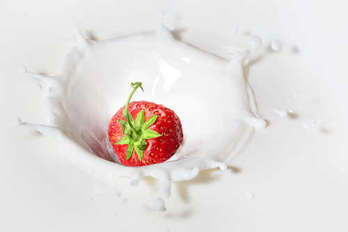 Strawberry dropped into milk with splash