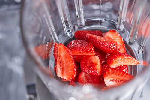 Close up of juicy strawberry slices in a blender. Cooking healthy berry dessert. Top view