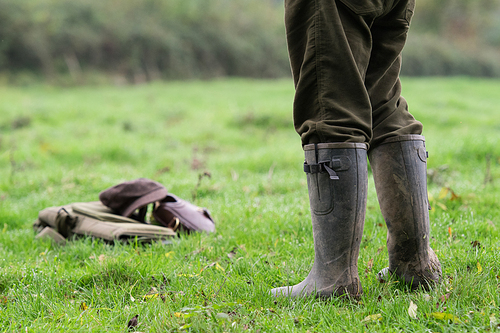 Game shooter stood in a field in his wellington boots