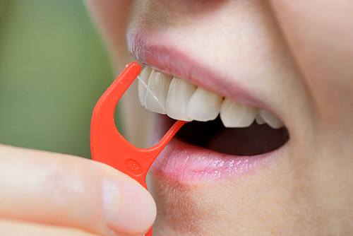 Details of Woman cleaning her teeth with an orthodontic flosser