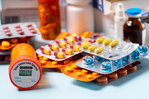 Pile of colorful medical pills in blisters and bottles on blue background. Drug and antibiotics prescription for treatment medication.