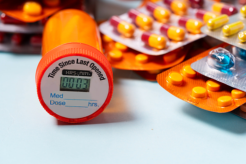 Pile of colorful medical pills in blisters and bottles border on blue background. Drug and antibiotics prescription for treatment medication.