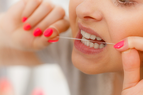 Everyday oral hygiene, dentistry concept. Woman cleaning her teeth using dental floss