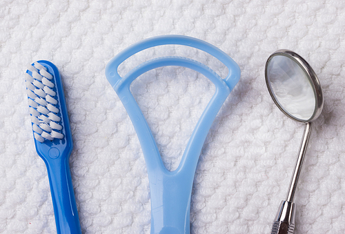 Oral hygiene health concept. Closeup dental tools blue toothbrush mirror and tongue cleaner on white towel