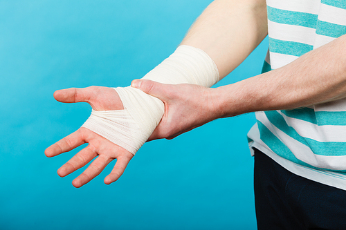 Pain and injury concept. Young man holds bandaged hand. Injured part of body. Medicine and healthcare.