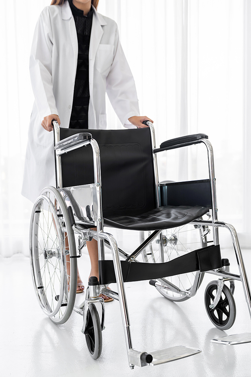 Closup of confident female doctor medical professional holding wheelchair examination room in hospital clinic