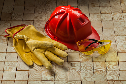construction gloves goggles and red helmet on woodn background