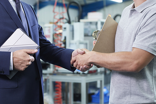 Close Up Of Business Owner With Digital Tablet In Factory Shaking Hands With Engineer