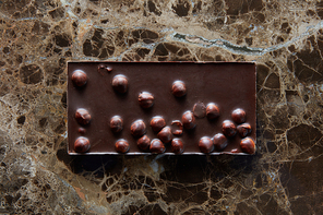chocolate bar with nuts on a dark background of a marble.
