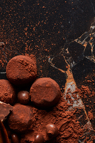 Chocolate truffles with cocoa powder macro on dark marble background.