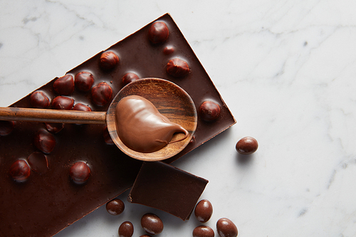 bar of chocolate and caramel with wooden spoon on a white background