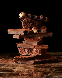 Roughly cut chunks of a chocolate bar on a marble dark background