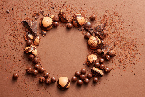 round frame of chocolates on a brown background with space for text