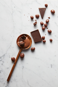 wooden spoon with chocolate and chocolate balls on a white marble background