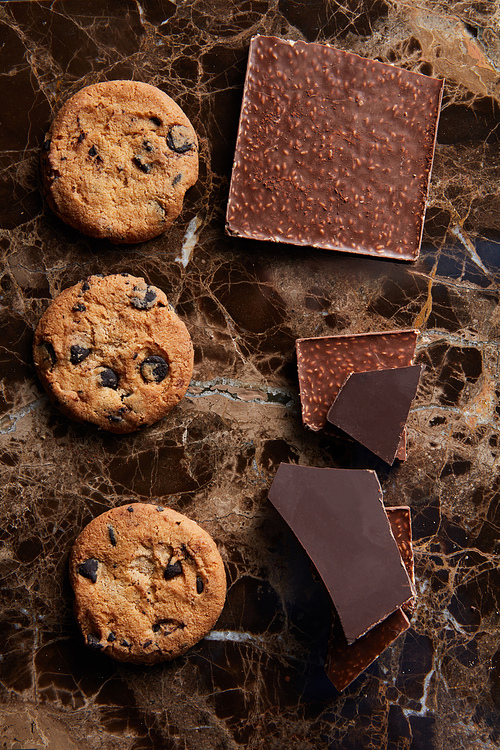 pieces of chocolate and cookies with chocolate Drops on a dark marble background