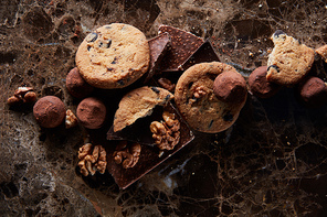 Fresh homemade chocolate chip cookies with chocolate candies in the dark marble background.