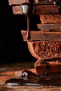 mountain of pieces of dark chocolate with drops of chocolate on a marble background