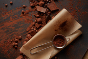 Cocoa powder in a sieve on parchment with chocolate on a dark background