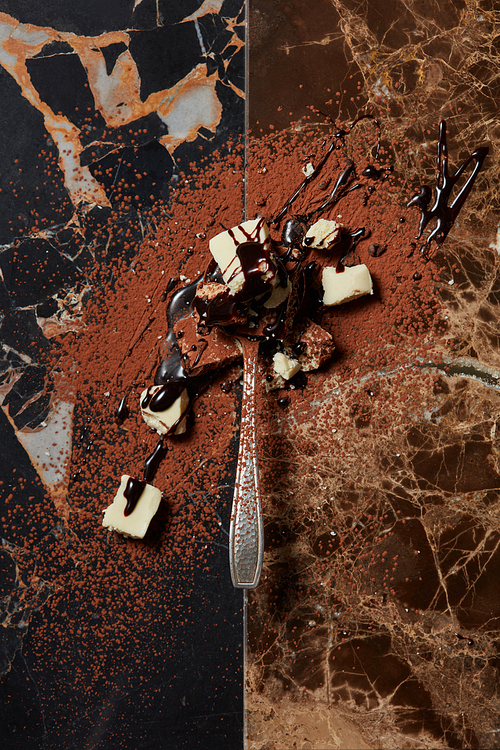 spoon with chocolate and chocolate syrup on a dark marble background