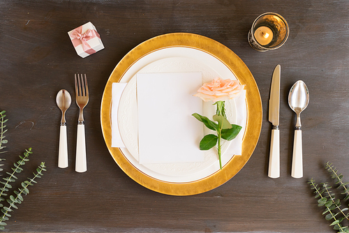 Tableware - set of plates and silverware with flowers on wooden background