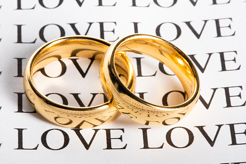 Two golden wedding rings with a word love close up