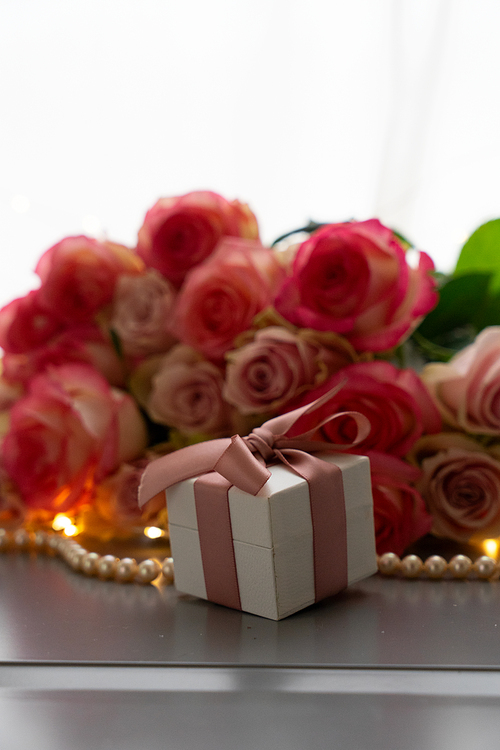 Rose fresh flowers bouquet on gray table by the window with pink heart gift box present close up