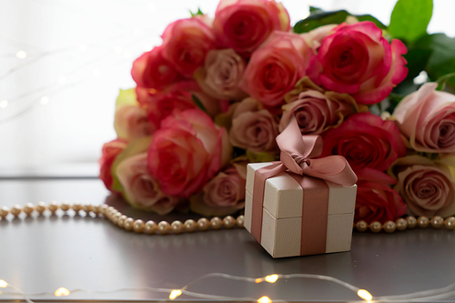 Rose fresh flowers bouquet on gray table by the window with pink heart gift box present