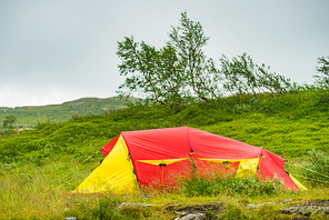 Camping. Red yellow tent on nature in summer. Holidays and travel.