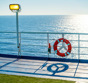 Ferry cruise railing in a blue ocean with round buoy and light beacon