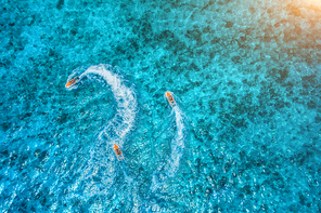 Aerial view of floating water scooter in clear blue water at sunset in summer. Holiday in Zanzibar, Africa. Top view of jet ski in motion. Tropical seascape with moving motorboat. Extreme. Boats