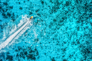 Aerial view of floating water scooter in transparent blue water at summer day. Holiday in Zanzibar, Africa. Top view of jet ski in motion. Tropical seascape with moving motorboat. Extreme. Boats