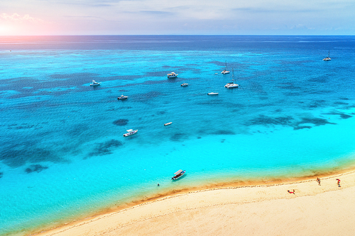 Aerial view of boats and yachts on tropical sea coast with white sandy beach at sunset in summer. Indian Ocean in Africa. Landscape with boat, people, transparent azure water, sky. Top view. Holidays