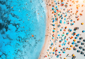 Aerial view of sandy beach with colorful umbrellas, swimming people, sea coast with transparent blue water at sunny day in summer. Travel in Mallorca, Balearic islands, Spain. Top view. Tropical