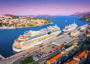 Cruise ship at harbor. Aerial view of beautiful large ships and boats at sunrise. Landscape with boats in harbour, city, mountains, blue sea. Top view of yacht. Luxury cruise. Floating liner in port