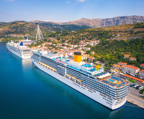 Aerial view of cruise ship in harbor. Top view of beautiful large ships and boats at sunny day. Landscape with harbour, city, buildings, mountains, blue sea. Luxury cruise. Floating liner in port