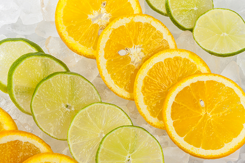 Rows of orange and lime slices laying on ice.